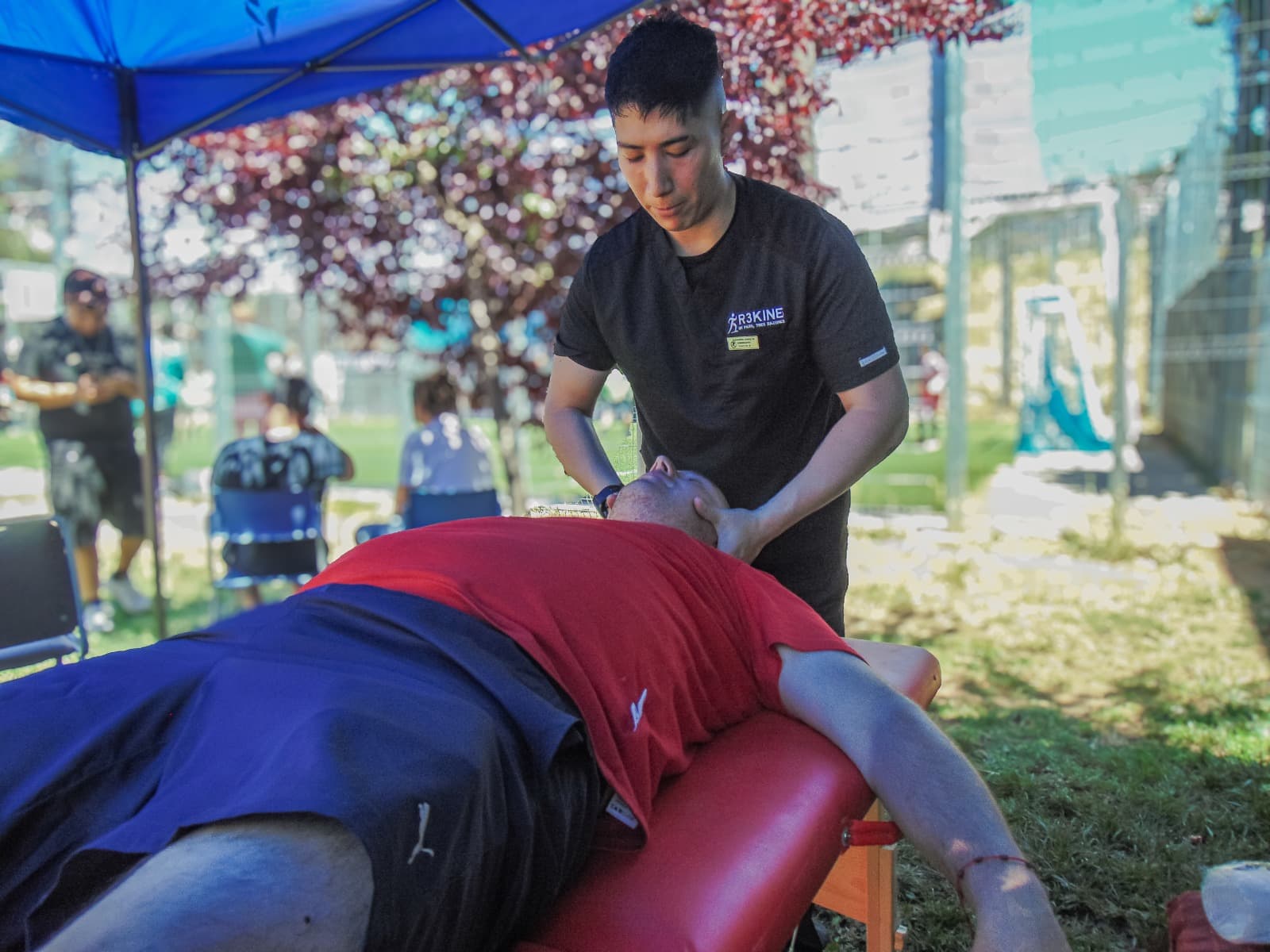 Kinesiólogo realizando terapia manual cervical a un paciente en camilla durante un operativo al aire libre